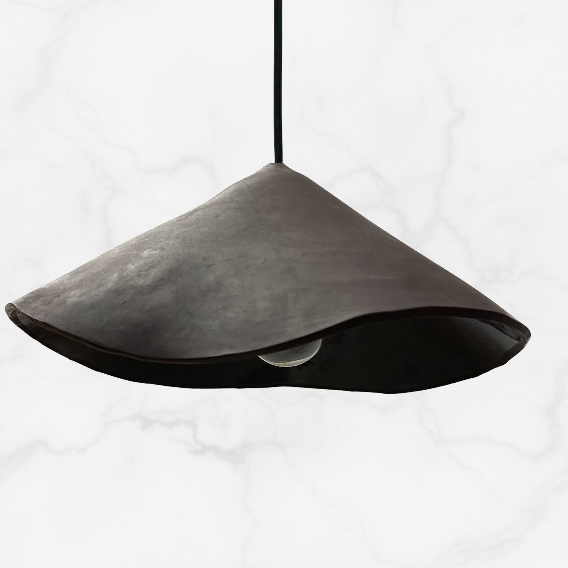 The Audrey pendant handcrafted ceramic pendant light Australia in matte charcoal finish with folded sculptural shade and exposed globe