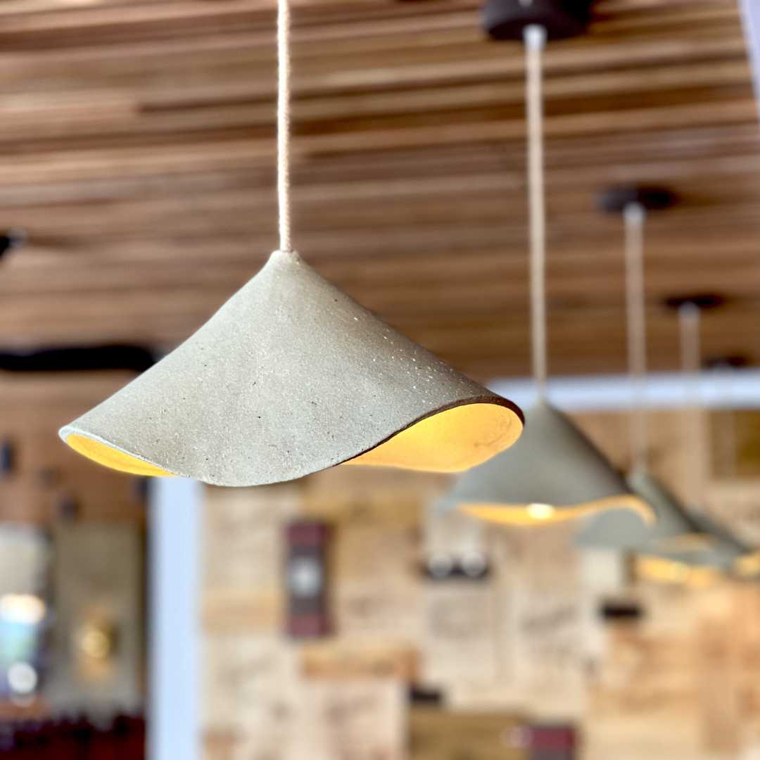 Audrey pendant lights suspended in hospitality venue featuring handmade ceramic shades with warm glow by Carver Lights