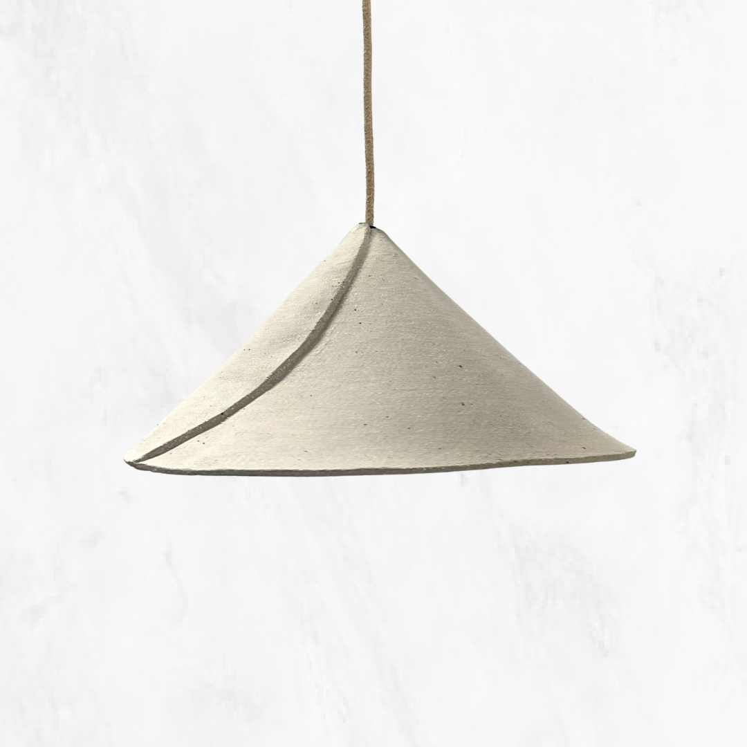 Beach Envelope handmade ceramic pendant light with a sculptural folded ceramic shade, raw sand-coloured finish and natural fabric suspension, shown against a light textured background.