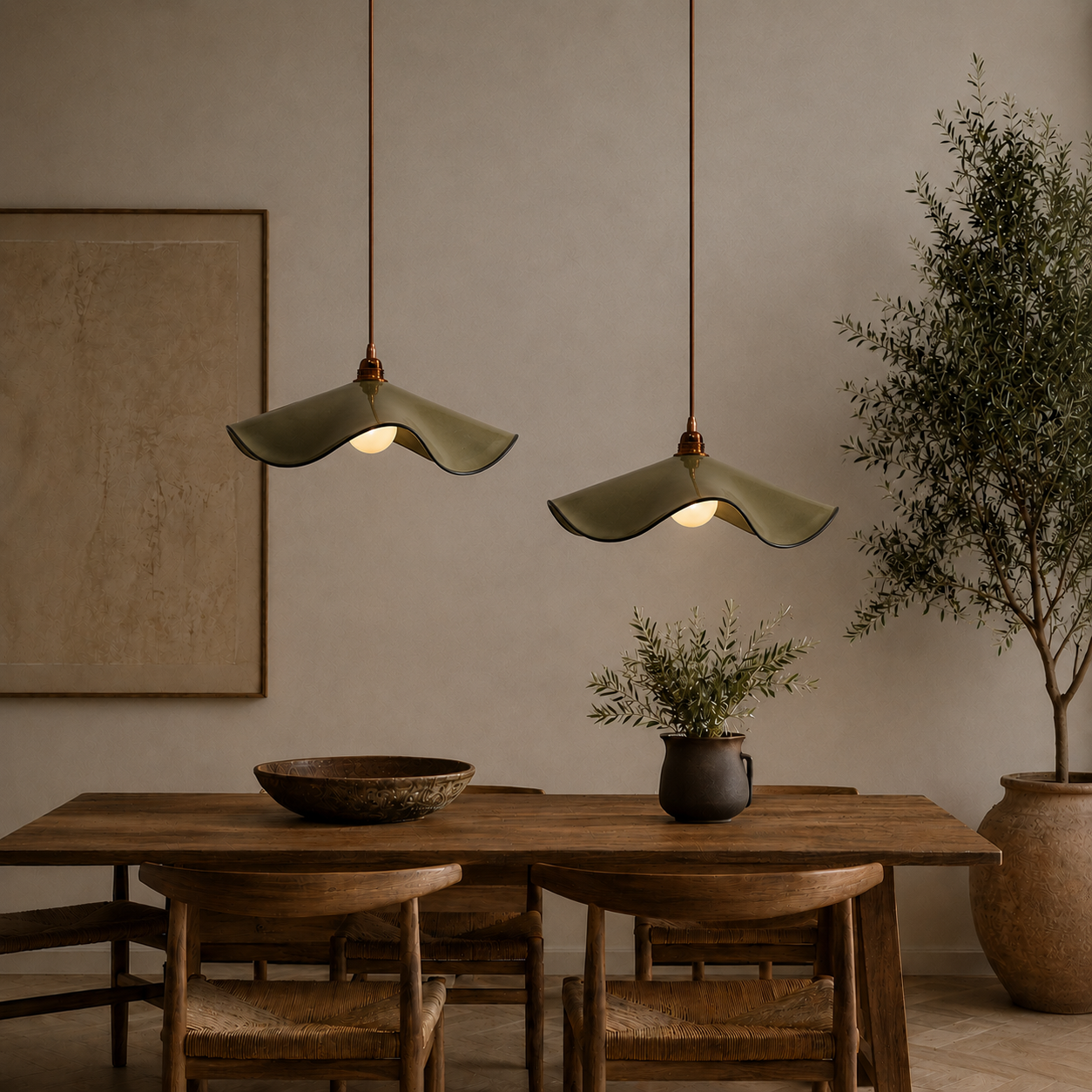 Two handcrafted Marilyn ceramic pendant lights in olive green glaze hanging at staggered heights above a timber dining table in a modern Australian home.