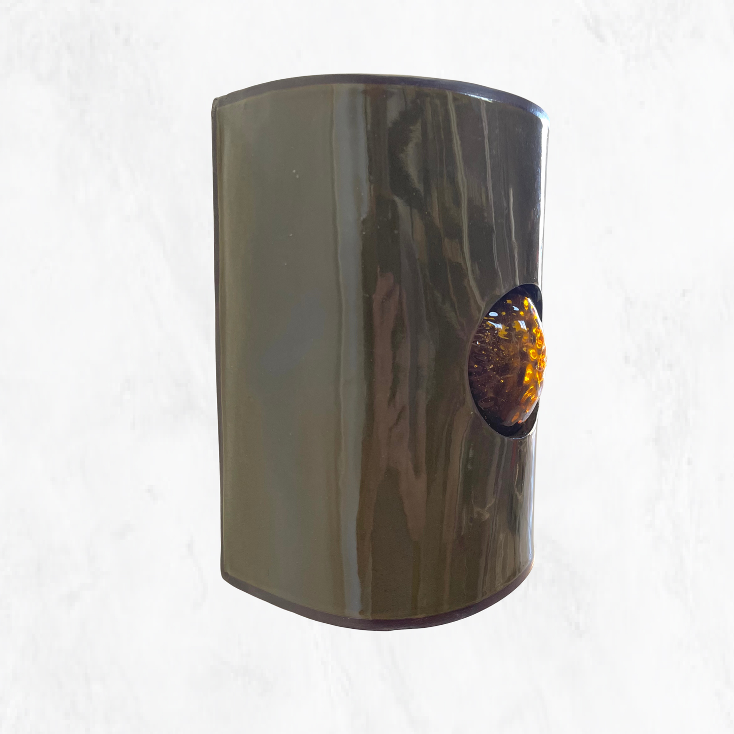 Handcrafted olive ceramic wall light featuring a textured amber glass insert, showcasing the rich olive glaze and warm amber glass detail against a clean background.