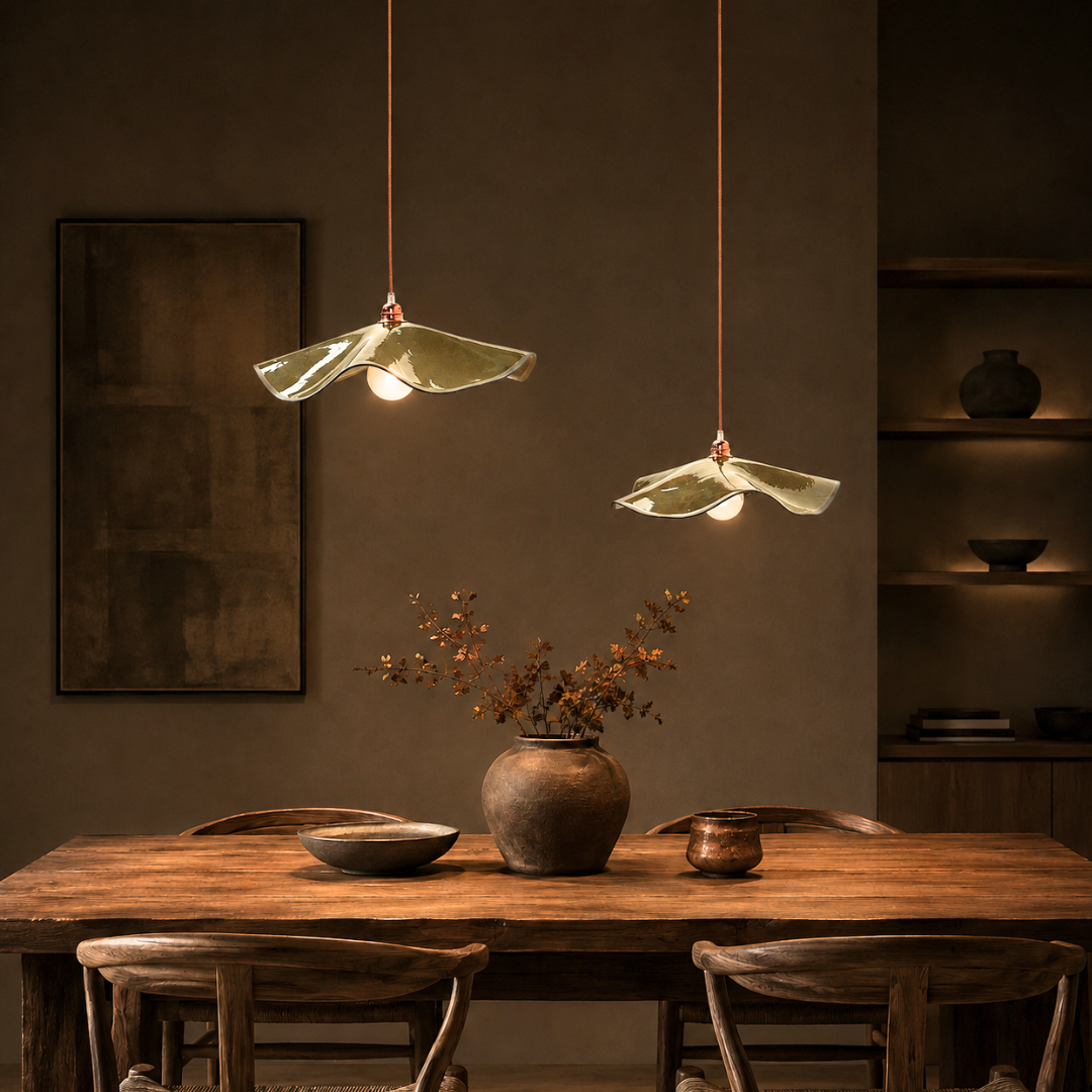 Two Olive Marilyn handmade ceramic pendant lights hanging at different heights above a timber dining table in a modern dining room, creating a warm ambient glow.
