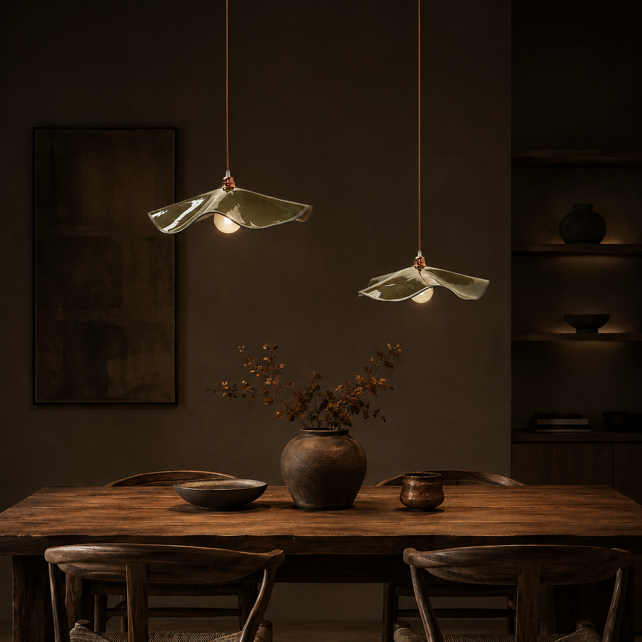 Two Olive Marilyn handmade ceramic pendant lights hanging at different heights above a timber dining table in a modern dining room, creating a warm ambient glow.