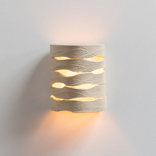 Panelled Wall Sconce handcrafted ceramic wall light with carved texture emitting warm ambient light on white background
