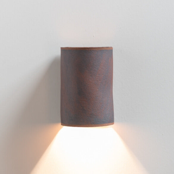 Rust Wall Sconce handcrafted ceramic wall light Australia lit showing warm ambient light cast upward and downward with rust-toned finish