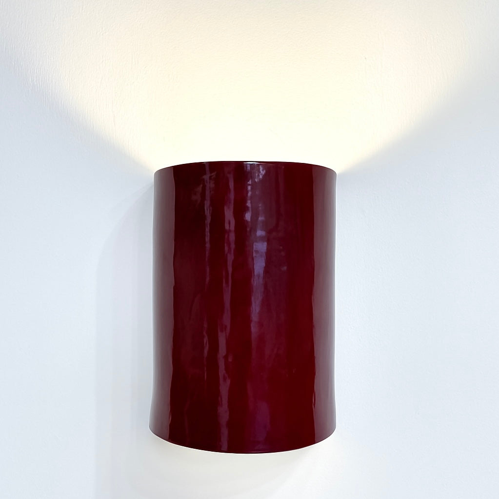 Shiraz Wall Sconce handcrafted ceramic wall light Australia lit showing warm ambient light cast upward and downward with deep red glossy glaze