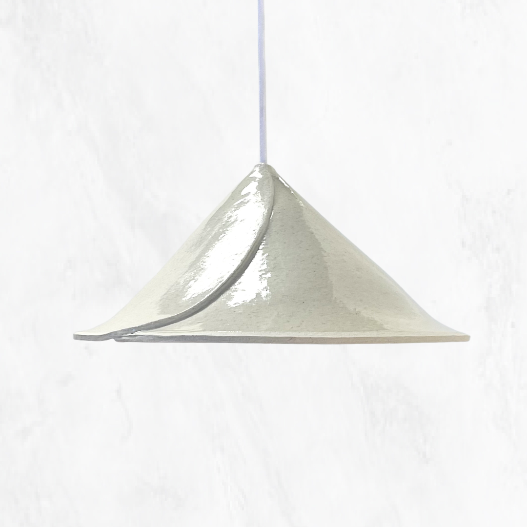 Stone Envelope handmade ceramic pendant light with a sculptural folded ceramic shade and glossy stone glaze, suspended on a white cord against a light textured background.