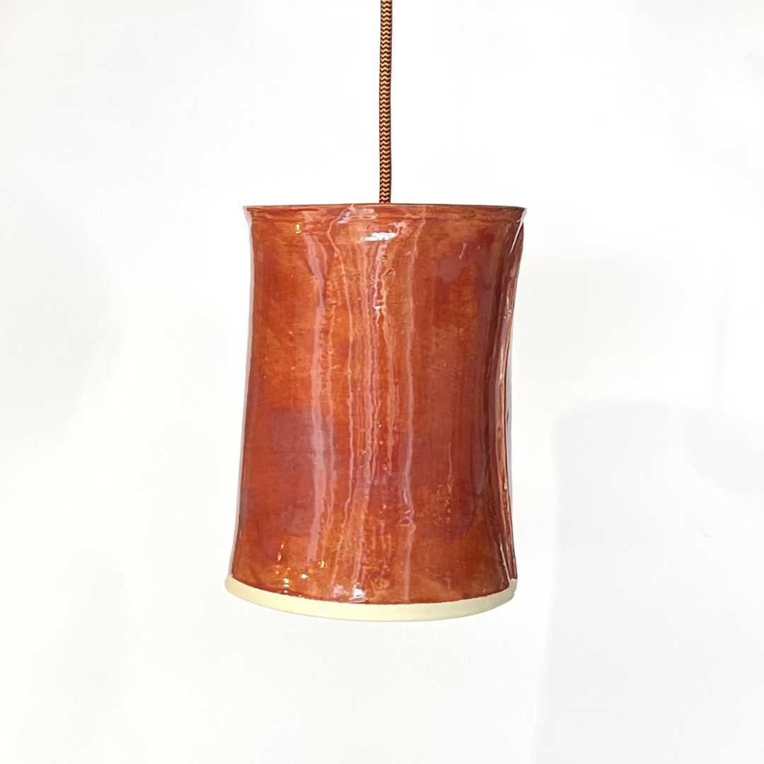 The Tumbler pendant handcrafted ceramic light Australia in burnt orange glaze with cylindrical form and warm ambient glow